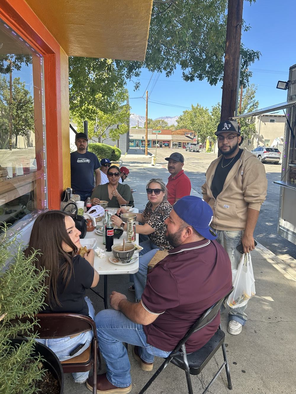 A big group eating at a table outside the store on Willow Street