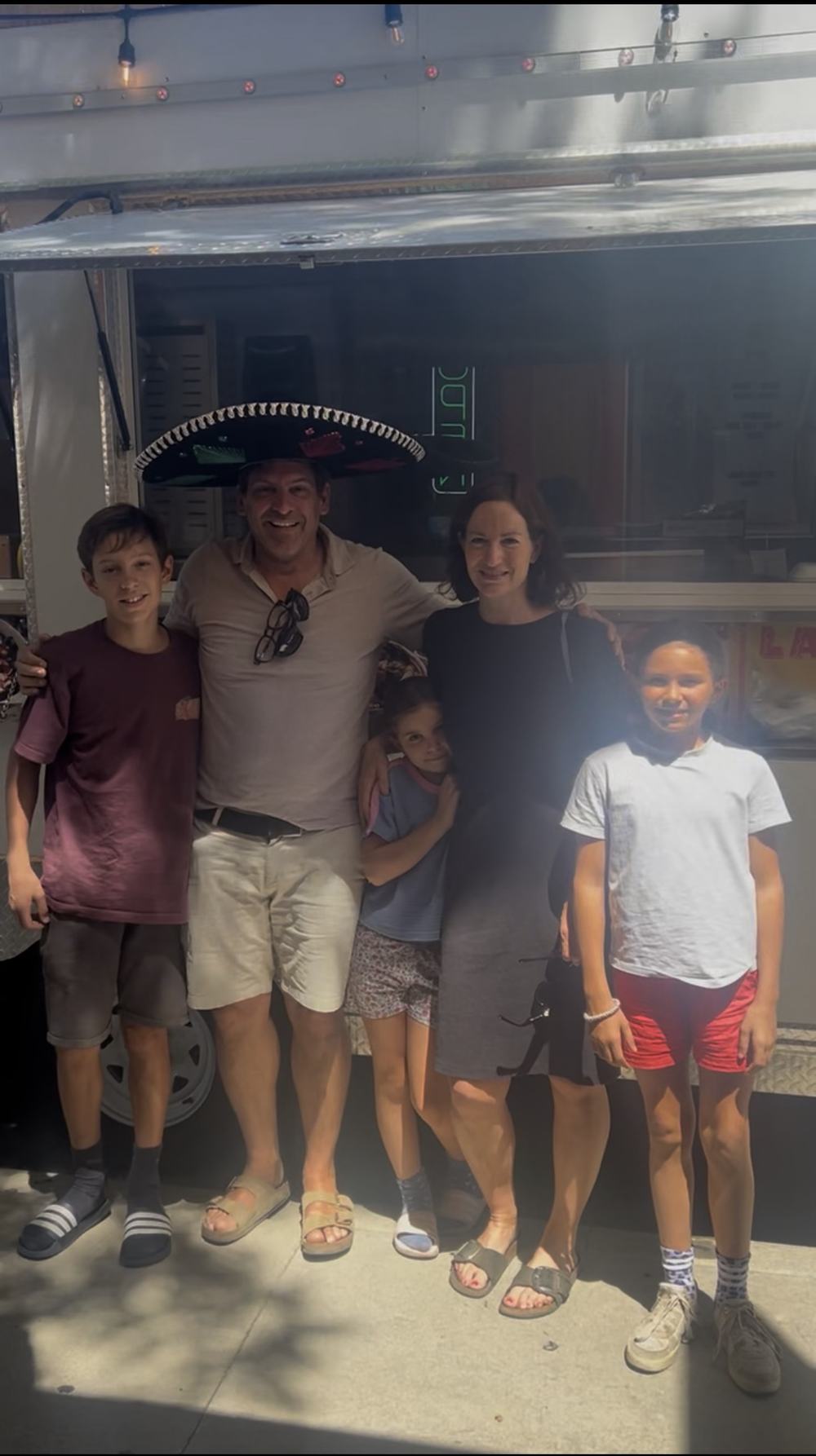A family visiting the taco truck, dad in a sombrero
