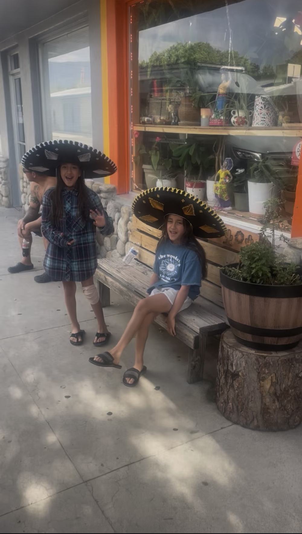 Two girls in sombreros on the carved bench outside