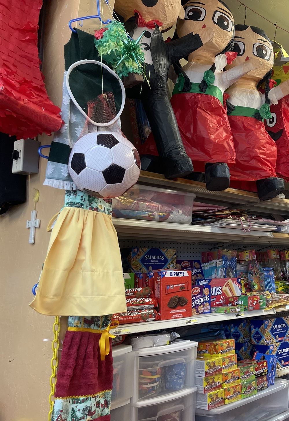 Adelita piñatas above shelves of Mexican candy and party supplies