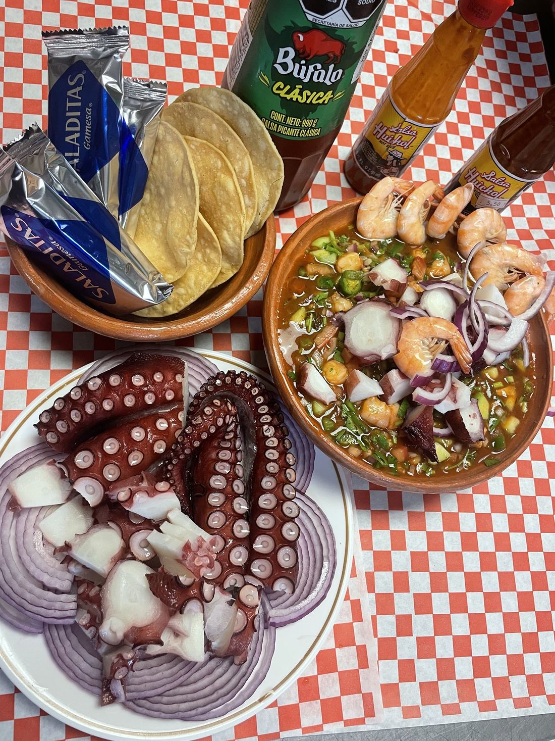 Octopus with red onion next to a seafood cocktail