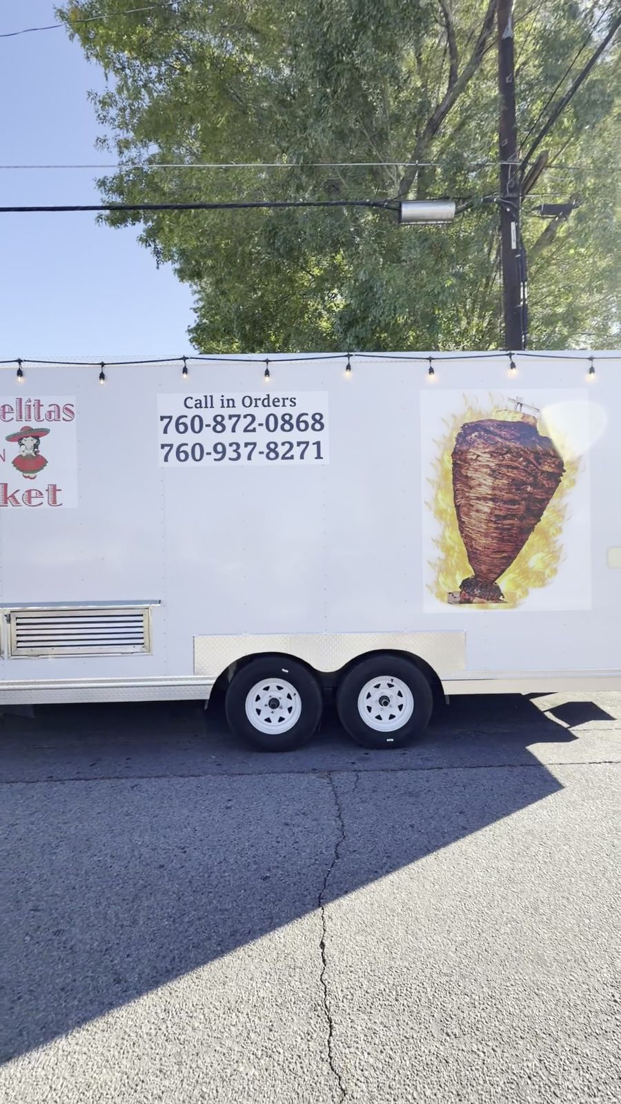 The Las Adelitas taco truck parked on the street, with call-in order numbers on the side